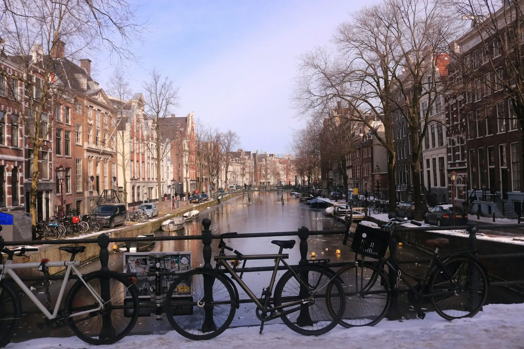 Bikes parked along a snow-covered canal street in Amsterdam