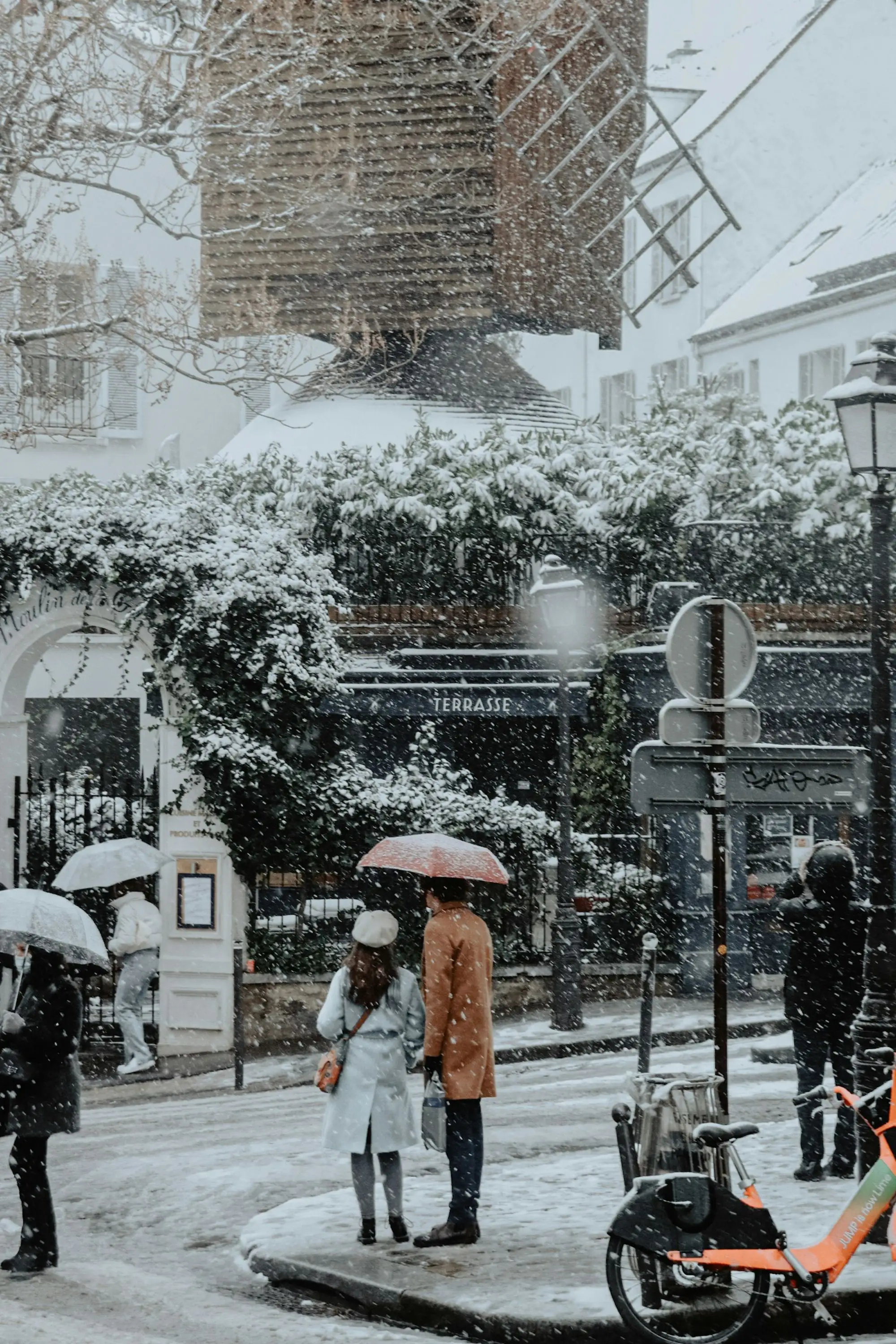 A woman with an umbrella walking along a snowy Paris street